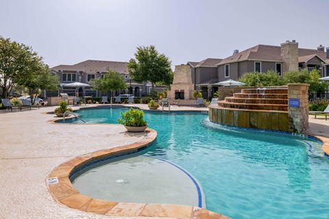 a large swimming pool with a house in the background