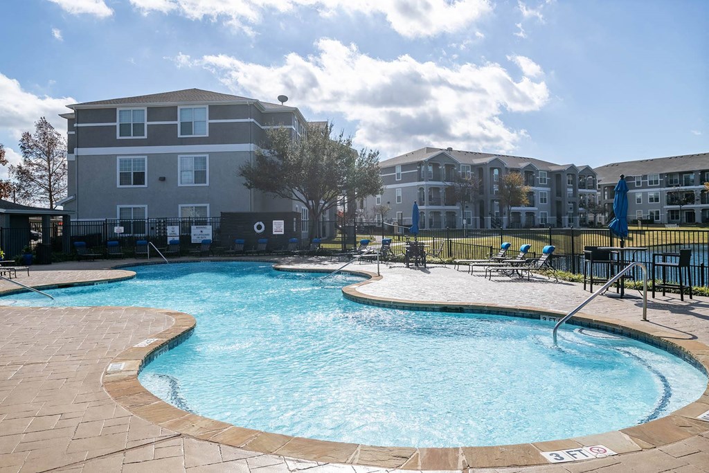 an outdoor pool with an apartment building in the background  at Orion Prosper, Prosper, Texas
