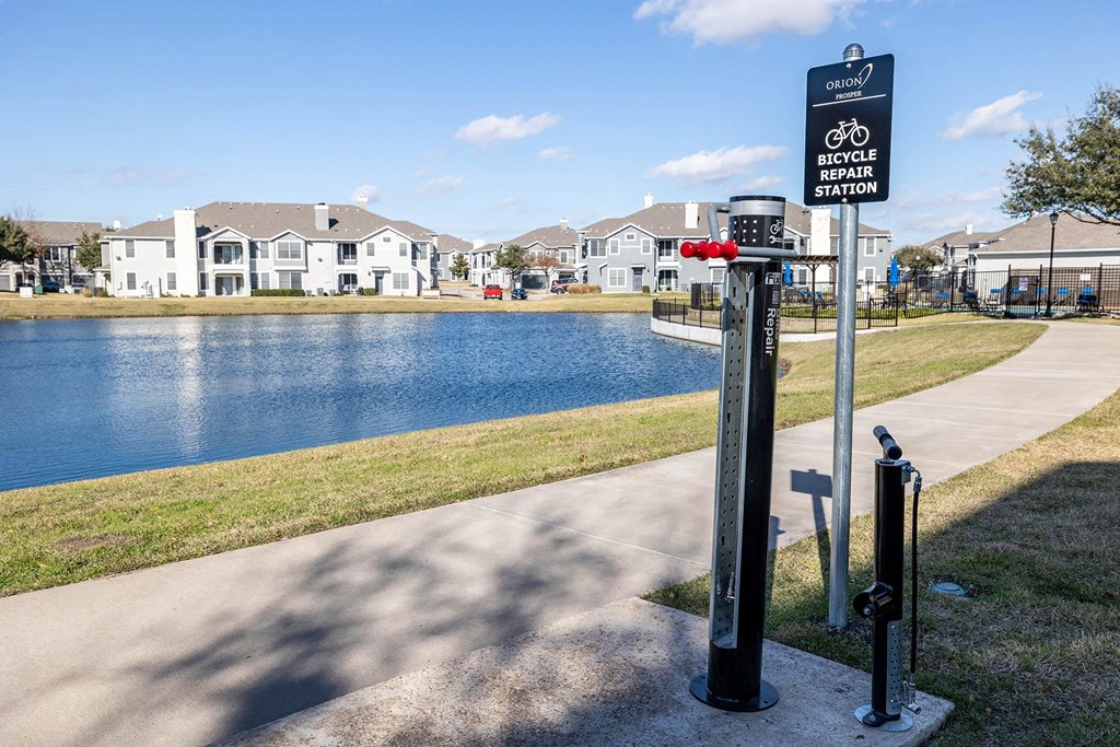 a sign for a bike path next to a body of water  at Orion Prosper, Prosper