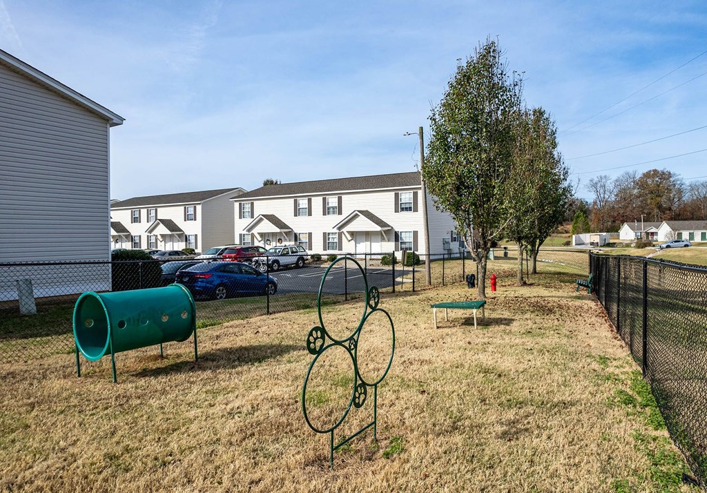 a park with a grassy area and houses in the background