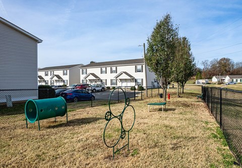 a park with a grassy area and houses in the background