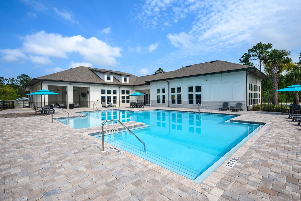 a large swimming pool with a house in the background