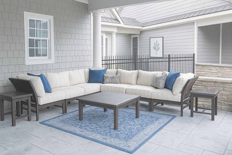 A white couch with blue pillows is on a patio.