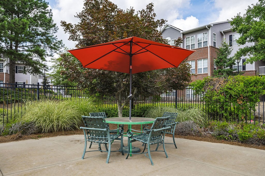 A red umbrella is in front of a green table.