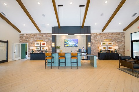 the lobby of a clubhouse with a dining area and a bar with blue chairs