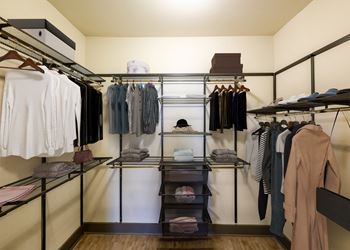 A walk in closet with clothes on shelves and hanging racks.