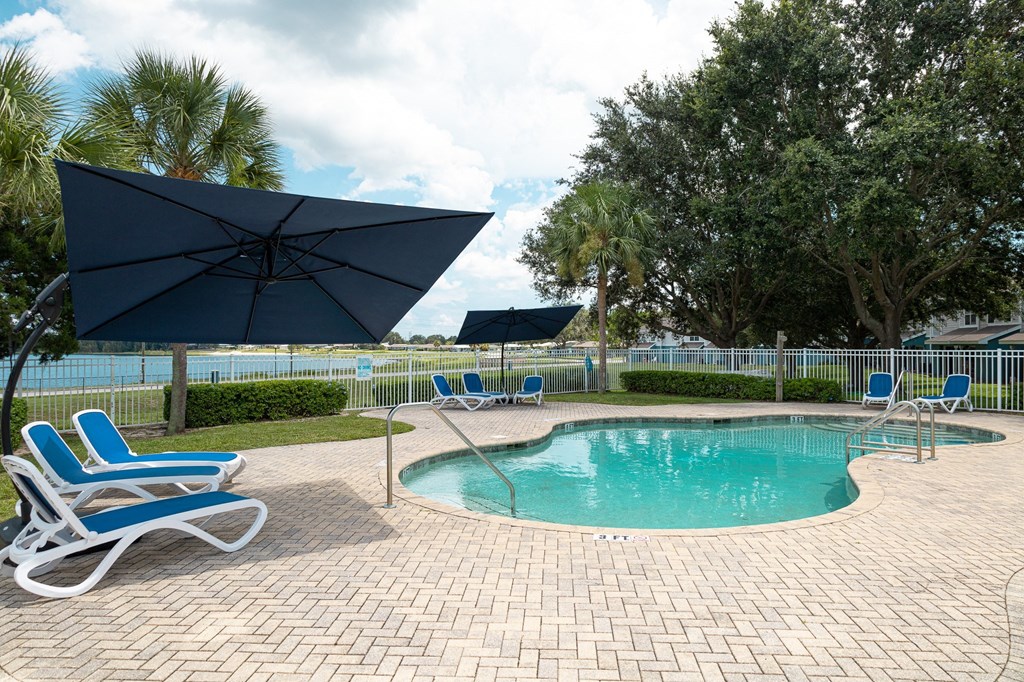 a resort style pool with chaise lounge chairs and umbrellas