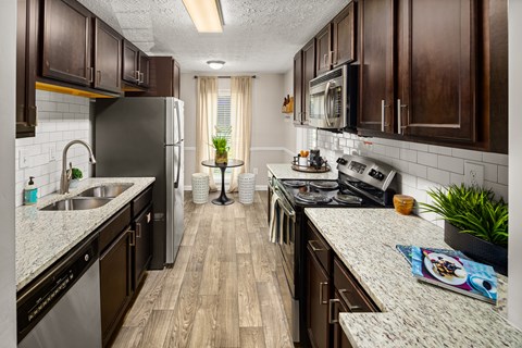 A kitchen with dark wood cabinets and a granite countertop.