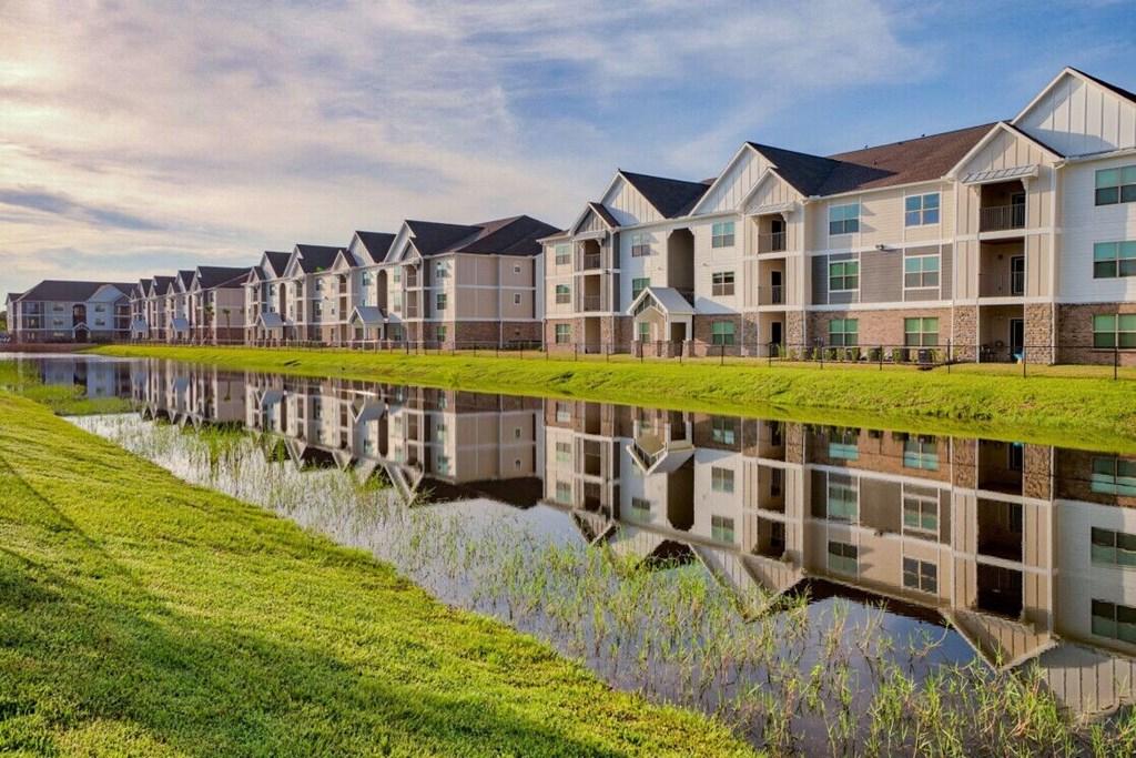 an apartment building is reflected in a retention pond