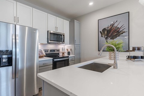 a white kitchen with stainless steel appliances and a sink