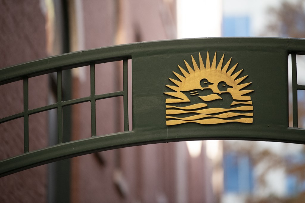 a green fence with a sticker of two ducks swimming in the water