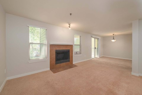 A living room with a fireplace and carpeting.