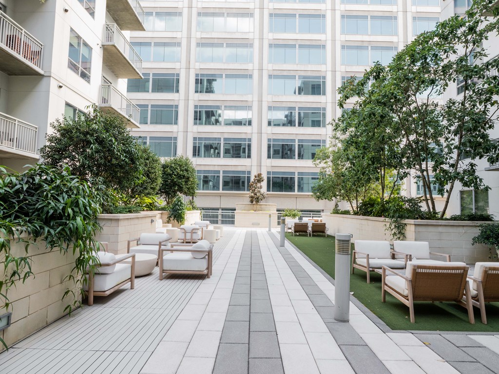 A patio with white chairs and a white wall.