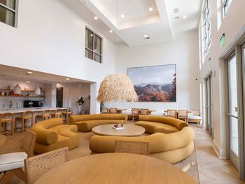 A modern living room with a large painting on the wall and a unique yellow sofa.