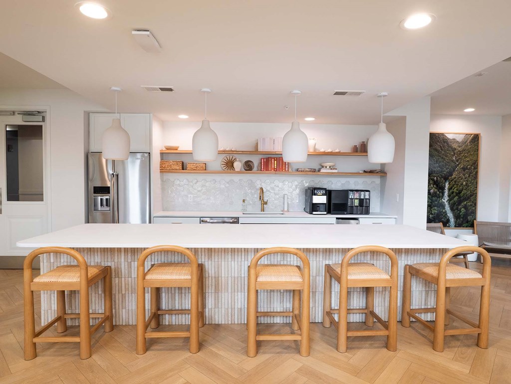 A kitchen with a white counter and wooden bar stools.