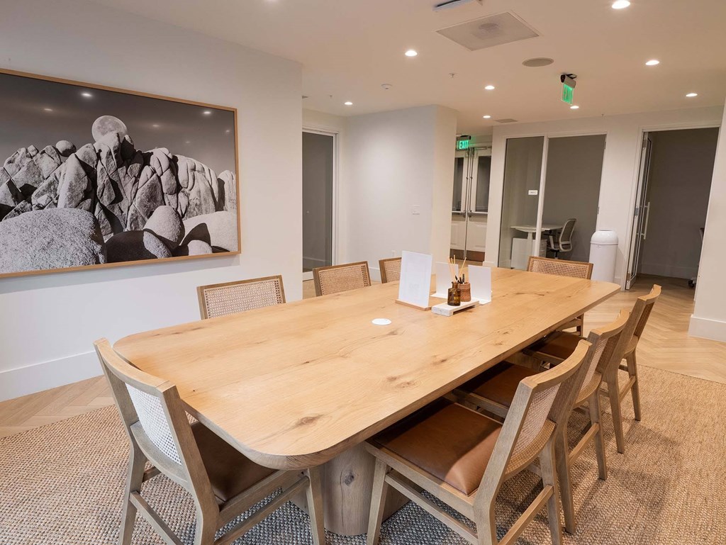 A large wooden table with chairs and a black and white photograph on the wall.