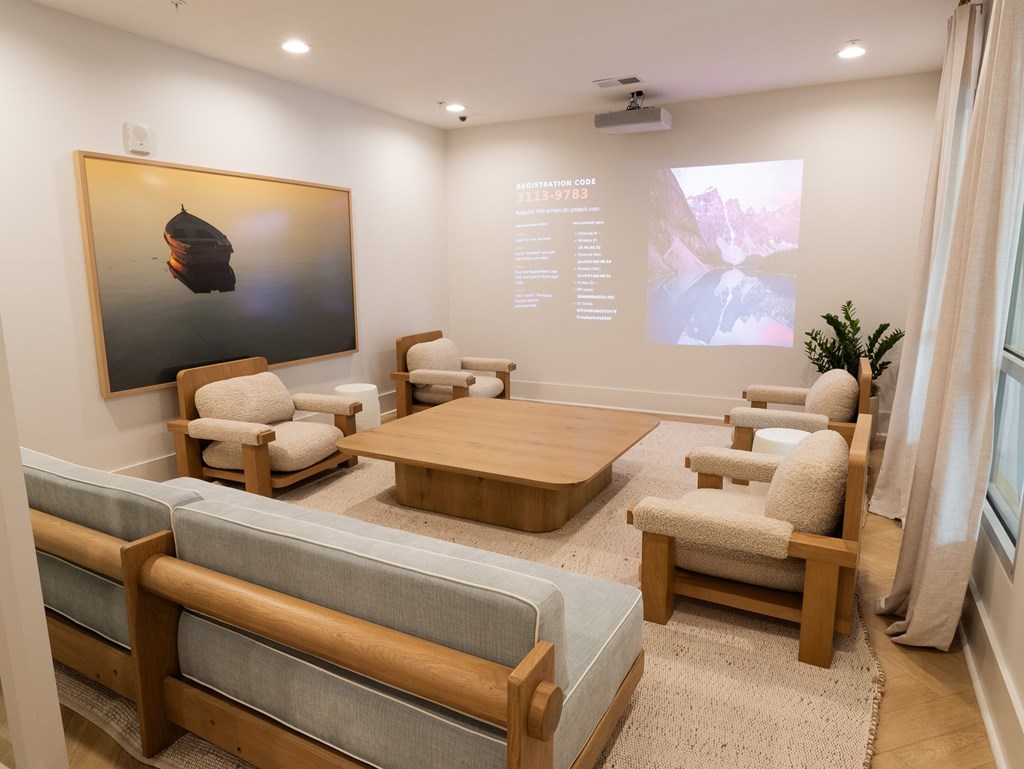 A modern living room with a large painting on the wall and a seating area with a sofa and chairs.