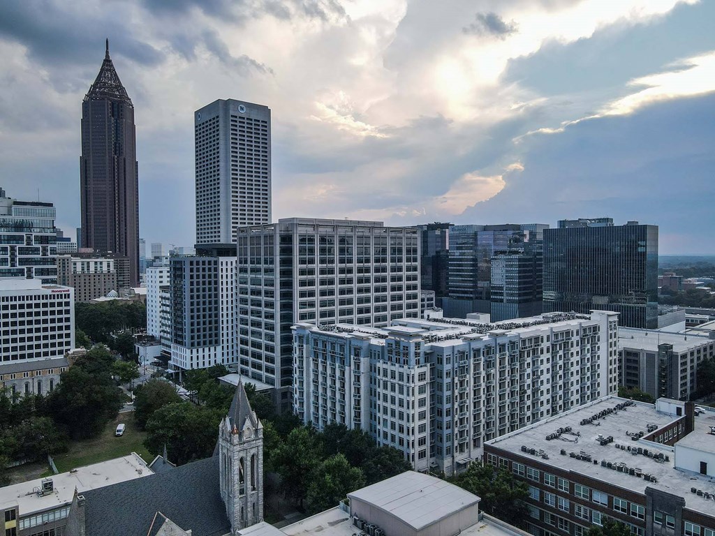 A cityscape with a mix of modern and older buildings under a cloudy sky.