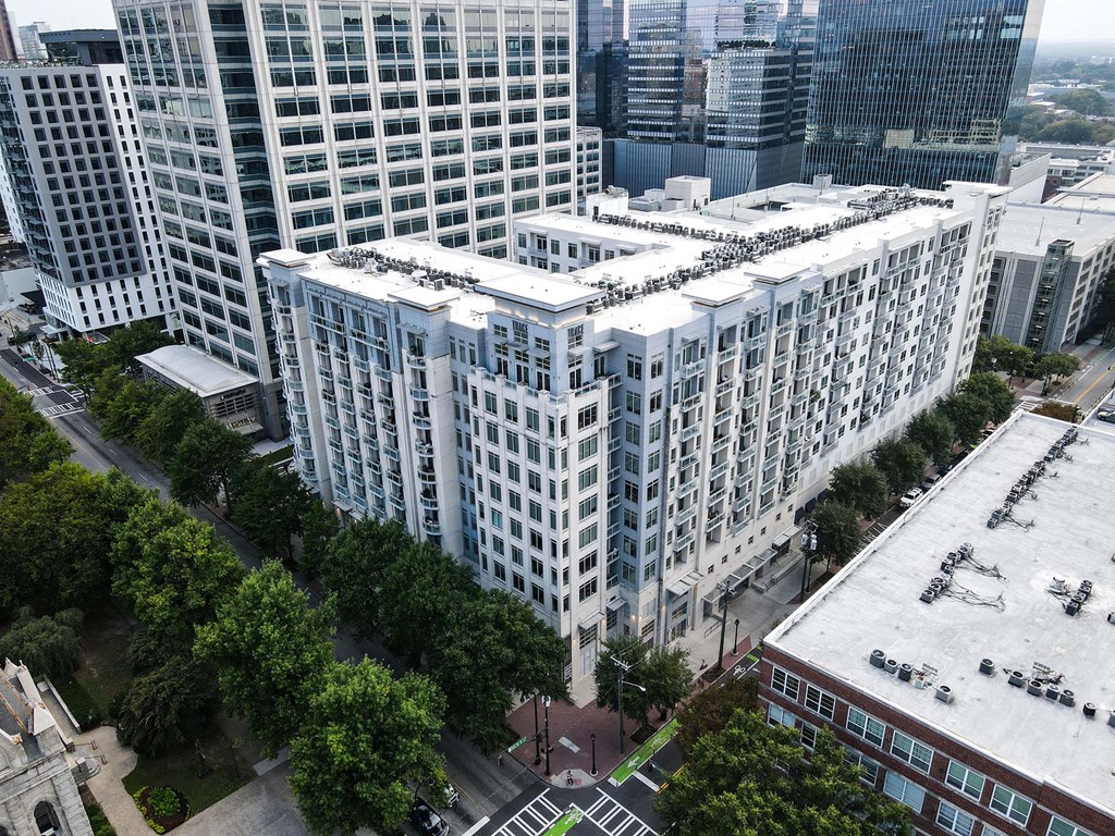 A large white building with a lot of windows is surrounded by trees.