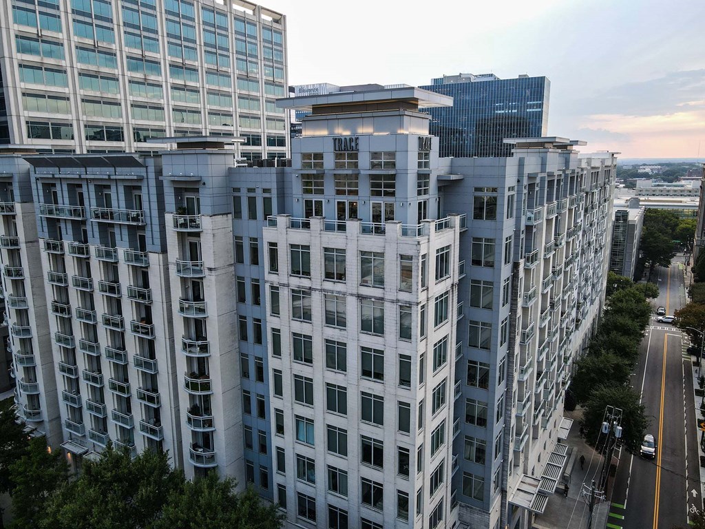 A tall white building with many windows is in the foreground of a city street.