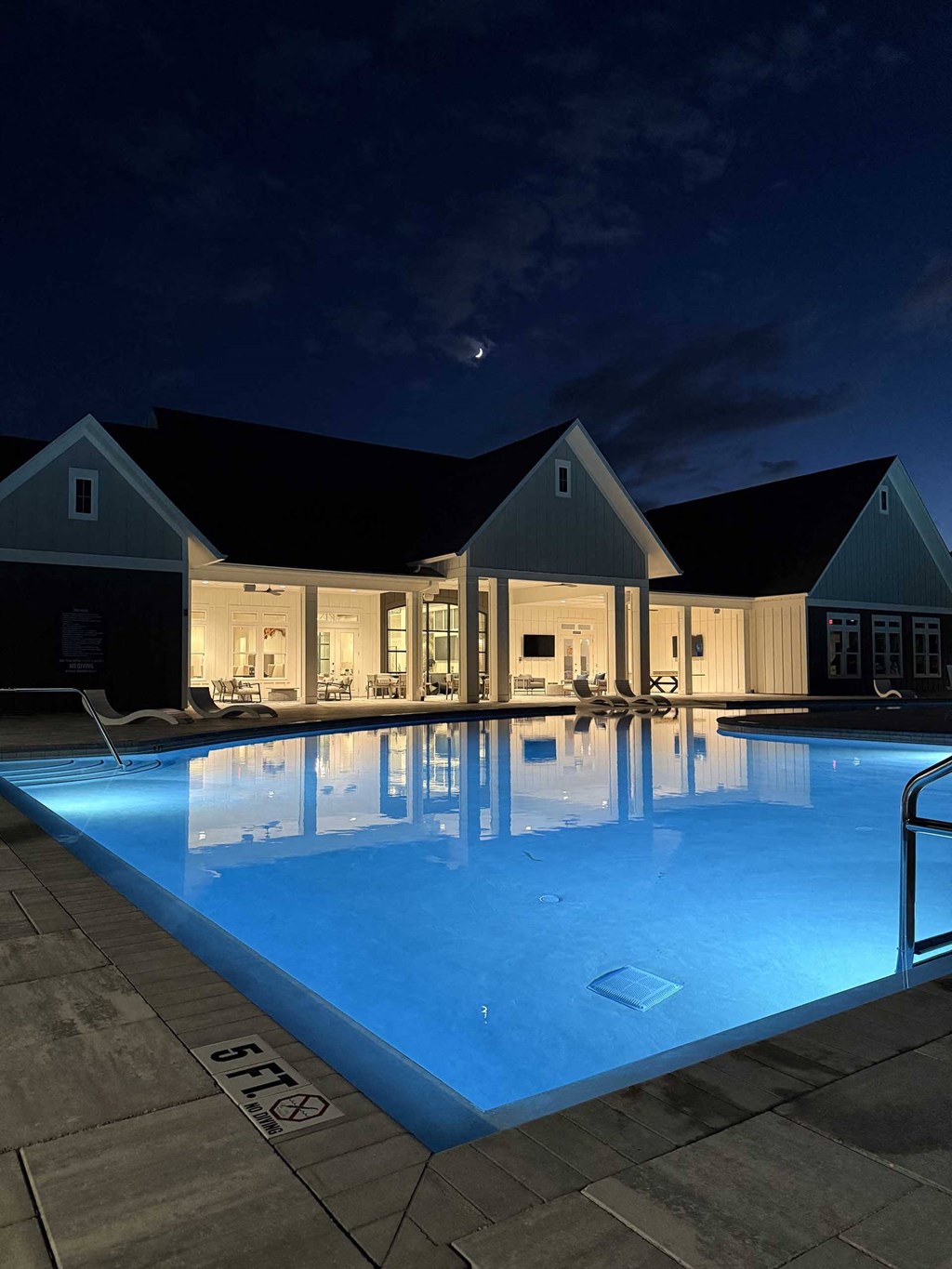 a swimming pool in front of a house at night