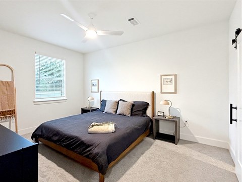A bedroom with a bed, nightstand, and window.