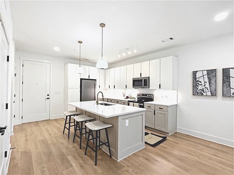 A kitchen with a white counter top and bar stools.