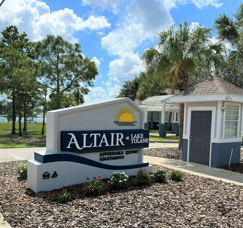 a sign that reads altair lake apartments with a building in the background - Photo Gallery 1