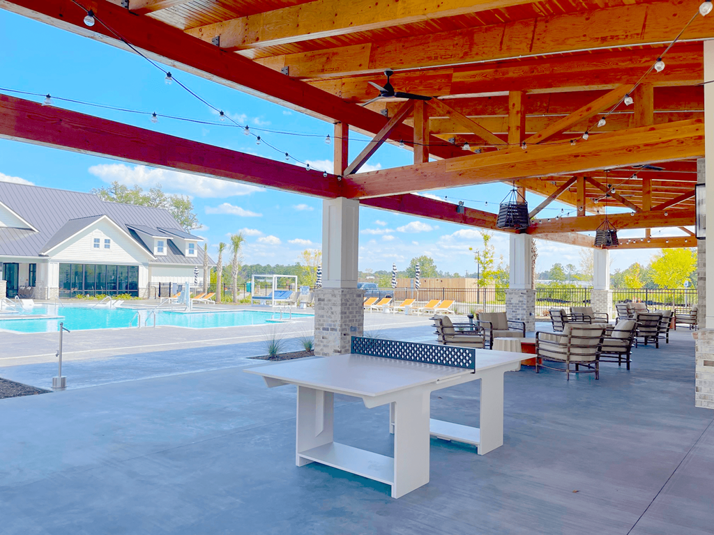 A patio with a table and chairs under a wooden pergola.