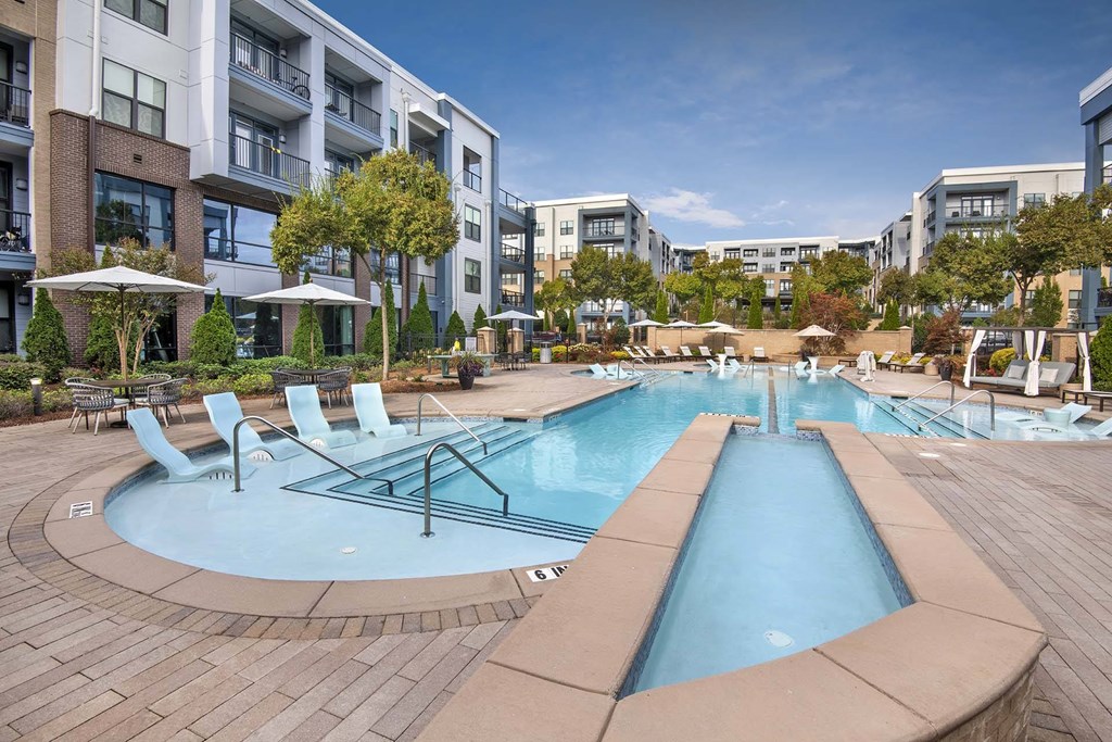 A large outdoor pool surrounded by lounge chairs and umbrellas.
