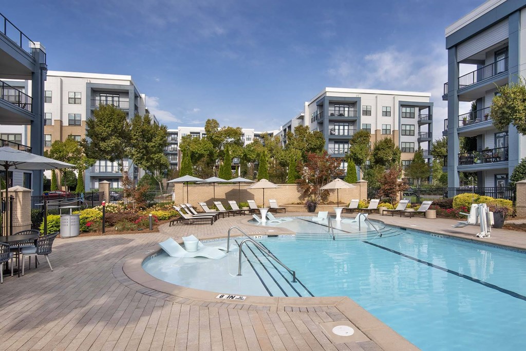 A large outdoor swimming pool surrounded by lounge chairs and umbrellas.