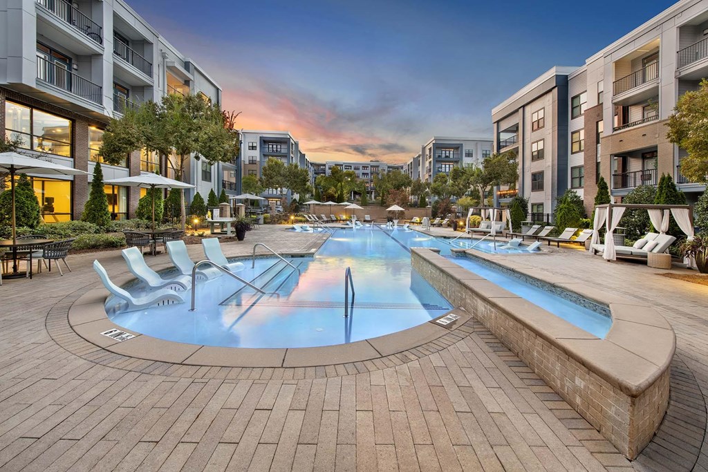 A large outdoor swimming pool surrounded by lounge chairs and umbrellas.