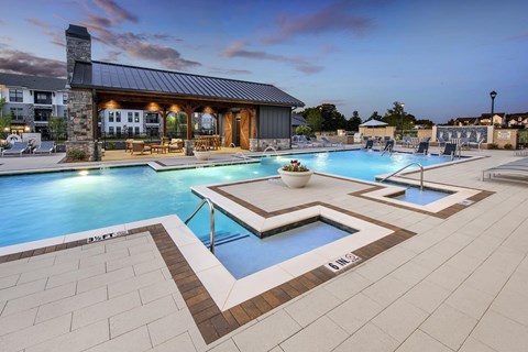 A large outdoor swimming pool with a hot tub in the middle.
