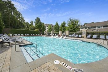 a resort style pool with lounge chairs and a building in the background