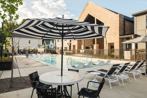 A black and white striped umbrella is over a table with chairs around it.