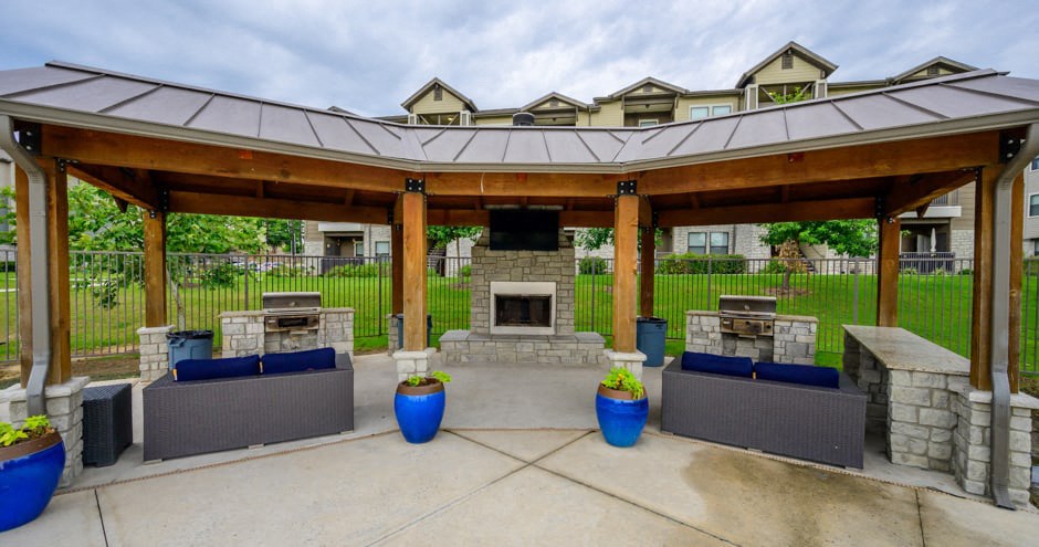 a covered patio with a stone fireplace and a pavilion