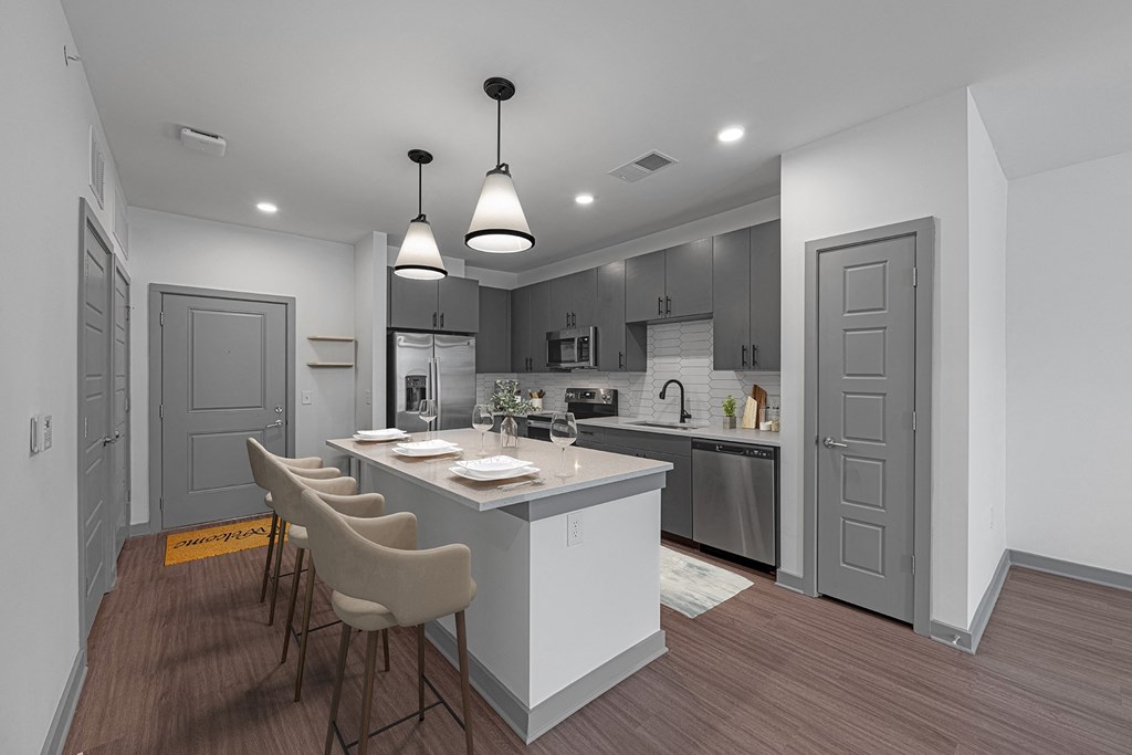 an open kitchen and dining room with a white island and white chairs