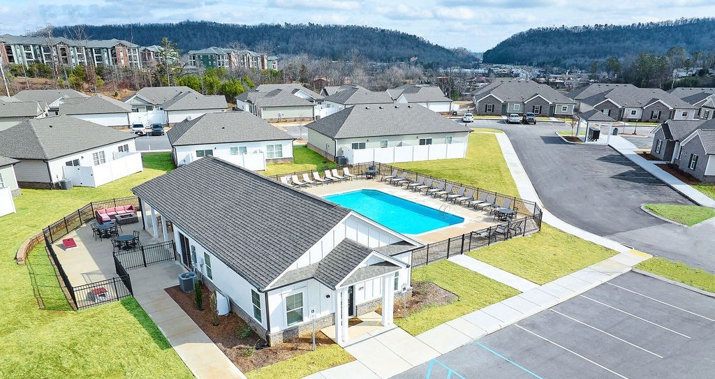 a house with a swimming pool in front of some houses