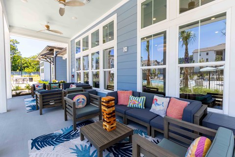 A patio with a couch, chairs, and a table with a pineapple on top.