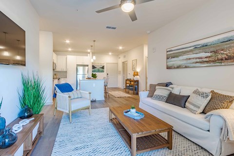 A living room with a white couch, a wooden coffee table, and a painting on the wall.