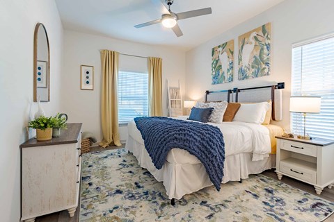 A bedroom with a bed, nightstand, and a ceiling fan.