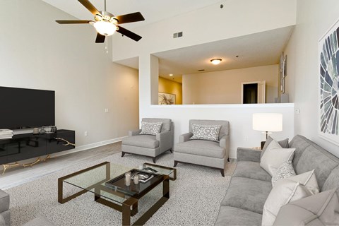 A living room with a grey couch, a glass coffee table, and a television.