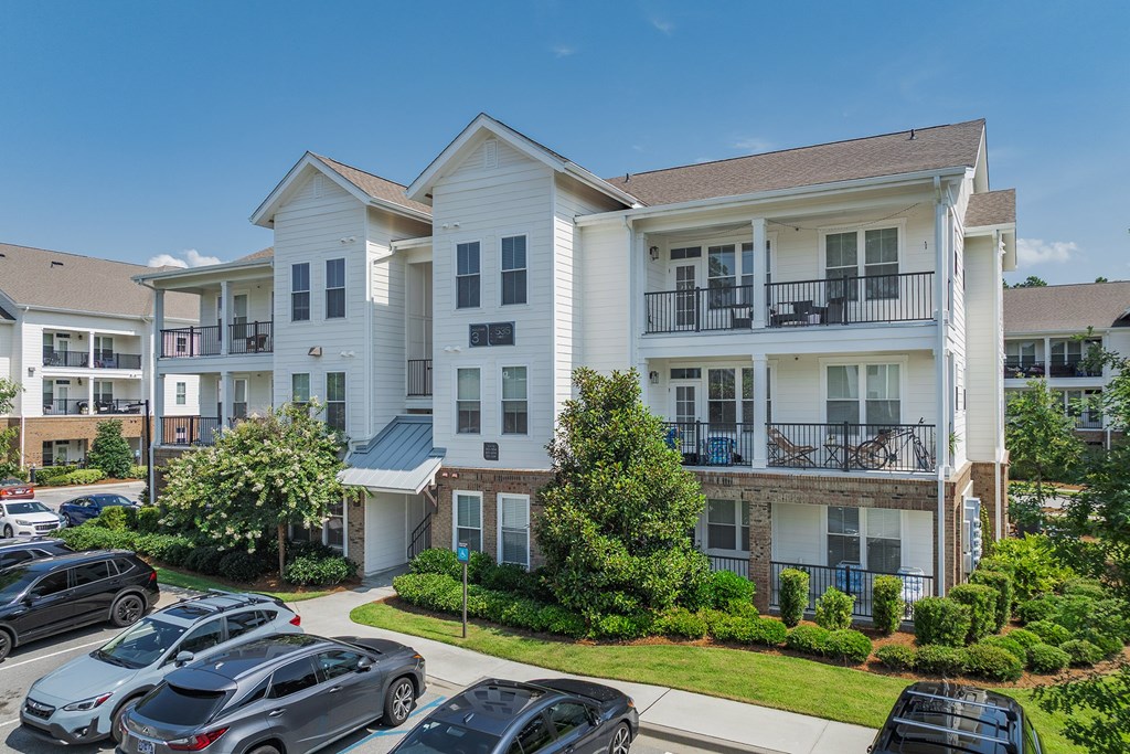 A large white apartment building with a parking lot in front.