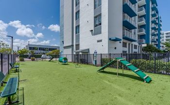 A playground with a green slide in front of a white building.