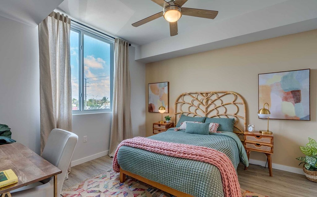 A bedroom with a bed, a chair, and a ceiling fan.
