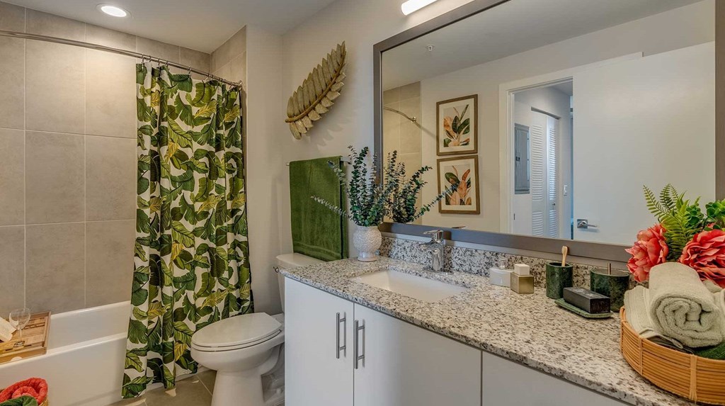 A bathroom with a white toilet, a green shower curtain, and a mirror.