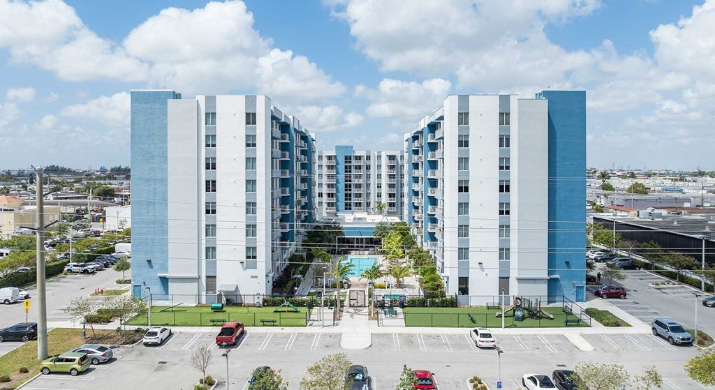 A large white and blue building with a parking lot in front.