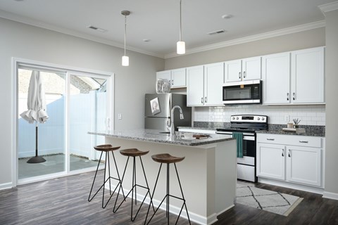 A kitchen with white cabinets and a marble countertop.