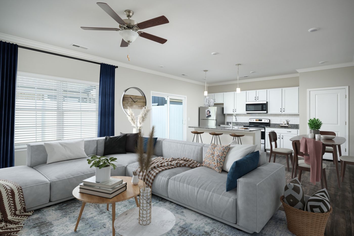 A modern living room with a grey sofa, a round table, and a ceiling fan.
