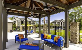 A patio with blue couches and a ceiling fan.